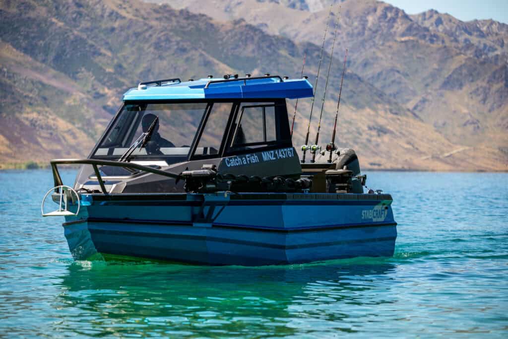 Angled side view of slowly moving fishing boat on Lake Hāwea