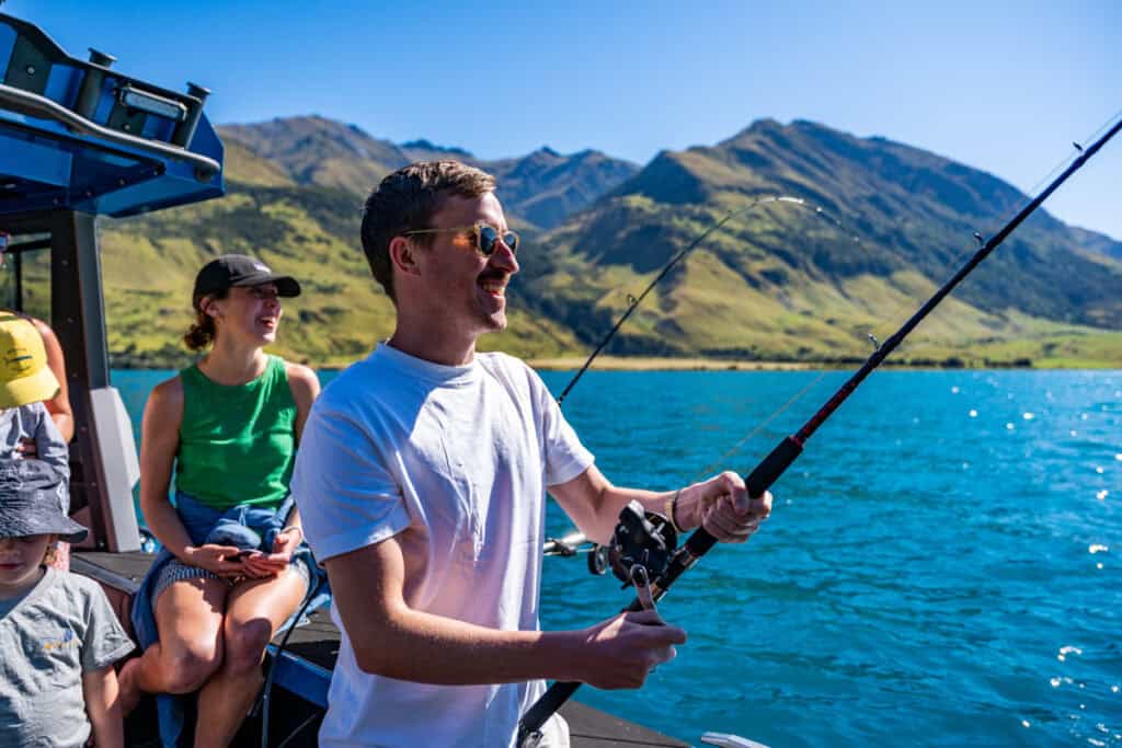 Man holding fishing rod on boat during sunny weather in New Zealand