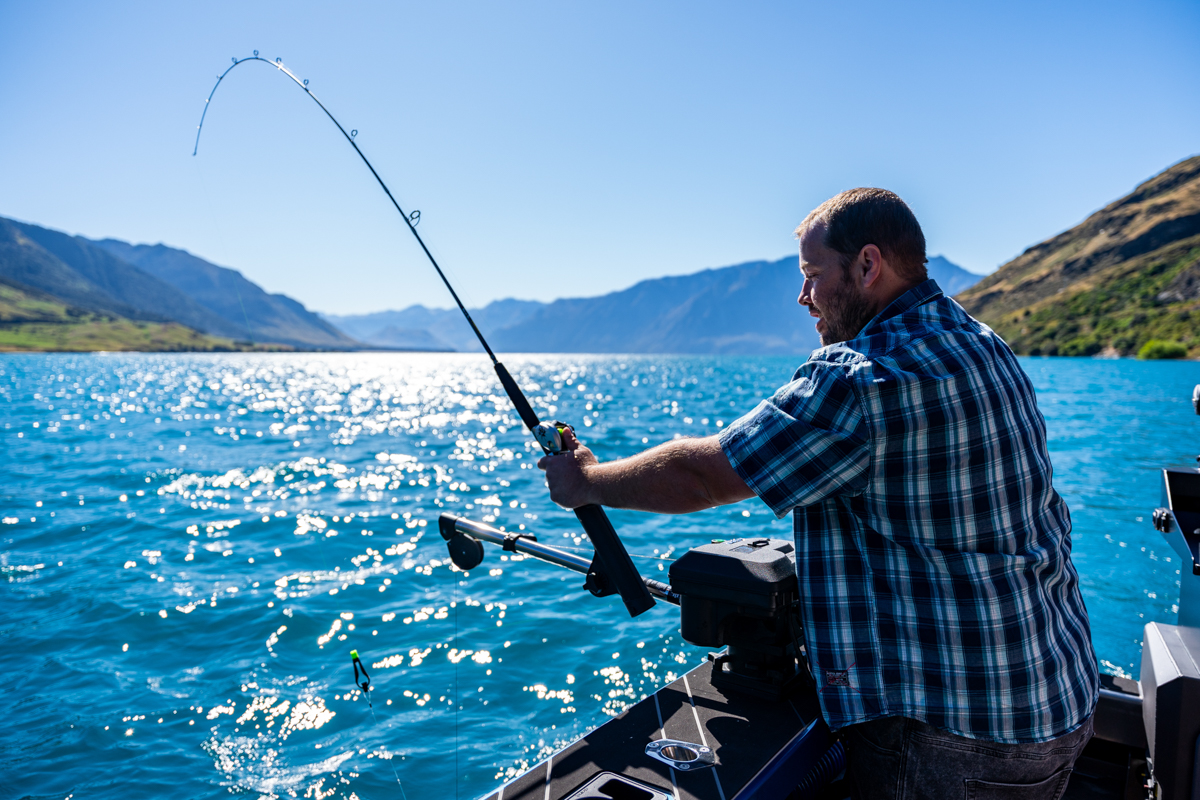 Skipper preparing a downrigger rod setup during a New Zealand lake charter