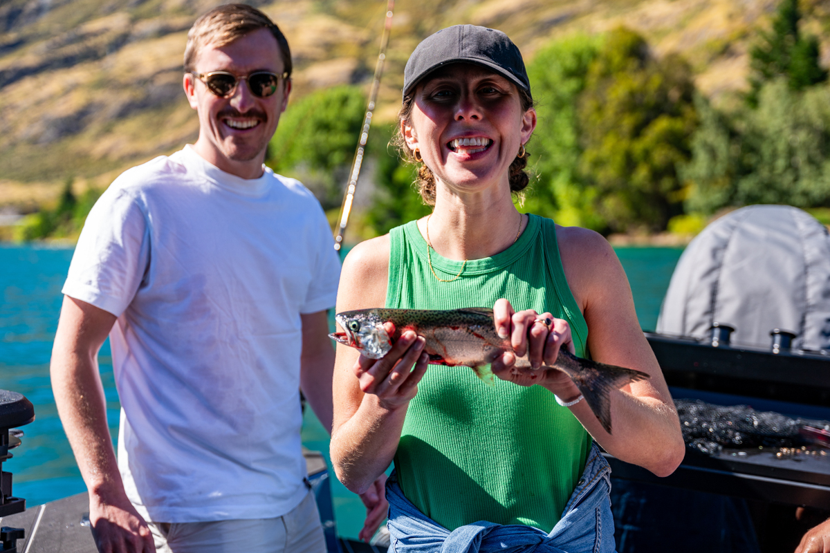 Woman showing off her freshly caught fish on a boat at Lake Hāwea, New Zealand