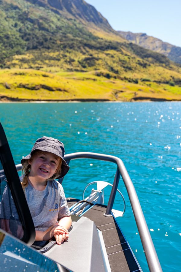 child-peeking-out-boat-window-fishing-charter-nz Child peeking out of the front window of a fishing boat on a New Zealand lake
