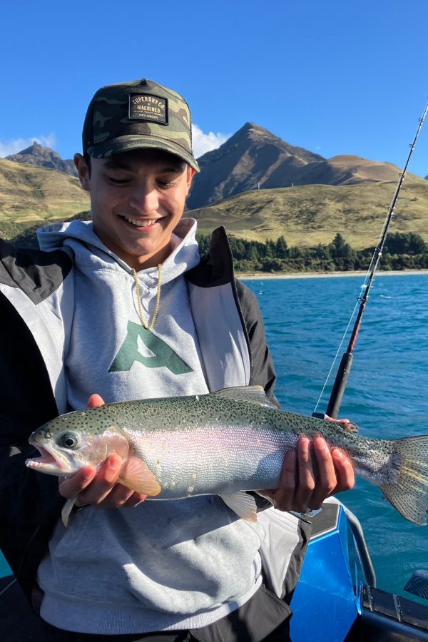 young-angler-holding-large-rainbow-trout-lake-hawea Young man holding a large rainbow trout in bright sunlight on Lake Hāwea