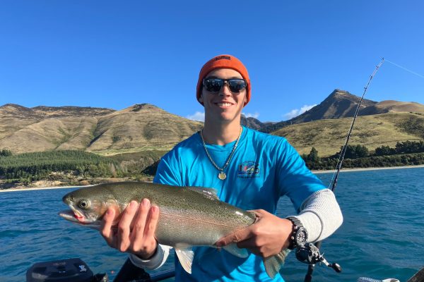 young-man-big-rainbow-trout-sunny-lake-hawea Young man proudly holding a large rainbow trout on a sunny day at Lake Hāwea