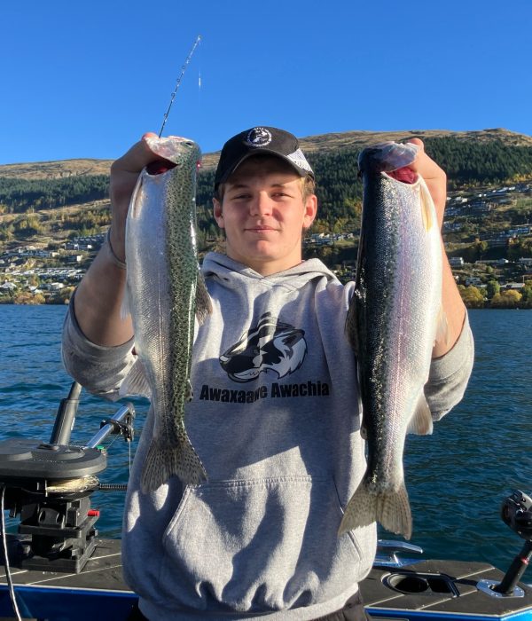 young-man-holding-two-trout-double-catch Young man proudly holding up two trout caught at the same time during a New Zealand fishing charter
